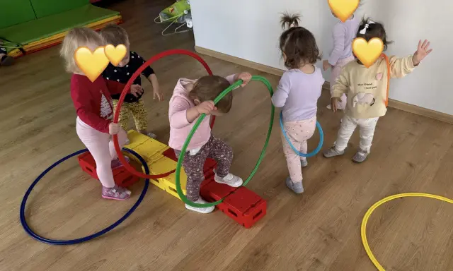 Dzieci bawią się kolorowymi hula hop na sali gimnastycznej. Radość i ruch to najlepsze zabawy z hula hop!