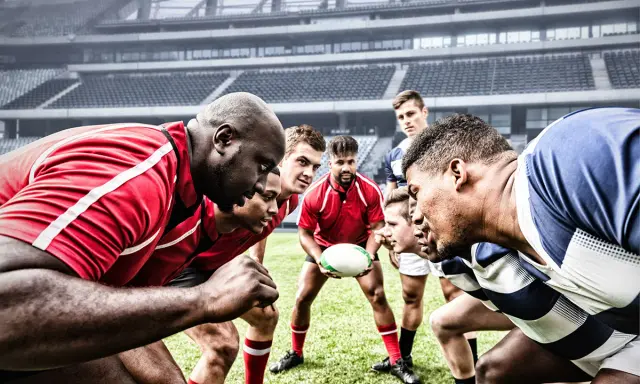 Zawodnicy rugby i futbolu amerykańskiego w skupieniu przed meczem na stadionie.