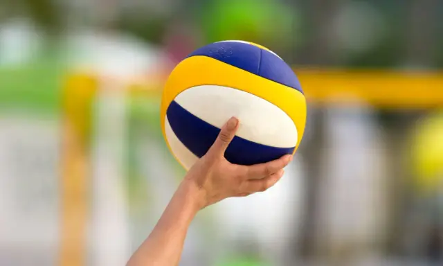 Dłoń trzyma piłkę do siatkówki, gotową do zagrywki. Napięcie przed tie break siatkówka.