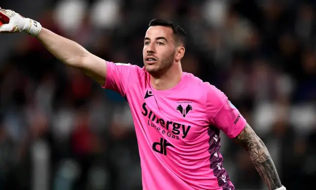 Bramkarz w różowej koszulce Hellas Verona wskazuje palcem, jakby chciał wiedzieć, ile trwa dogrywka w piłce nożnej.