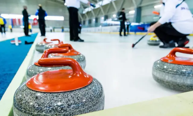 Kamienie do curlingu, każdy ważący ok. 20 kg, czekają na lodzie.