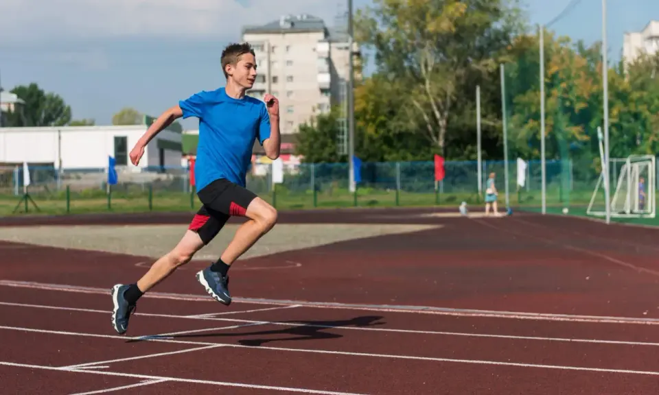 Młody biegacz na bieżni podczas zajęć sportowych dla młodzieży.