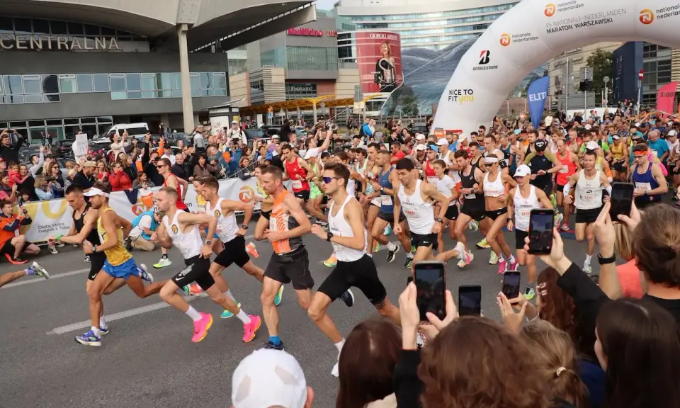 Uczestnicy maratonu w Warszawie, gotowi do startu. To świetny przykład, jak przygotować się do maratonu: trening, determinacja i wsparcie kibiców.