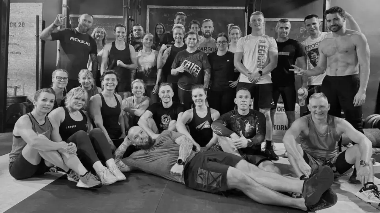 Uśmiechnięta grupa ludzi po treningu. Wszyscy ubrani w sportowe stroje, tworzą zgraną ekipę. To dowód na to, że sporty grupowe budują więzi.
