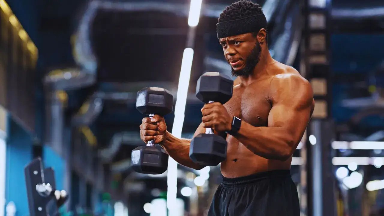 Mężczyzna wykonuje ćwiczenie hammer curl z hantlami, skupiony na budowaniu bicepsów.