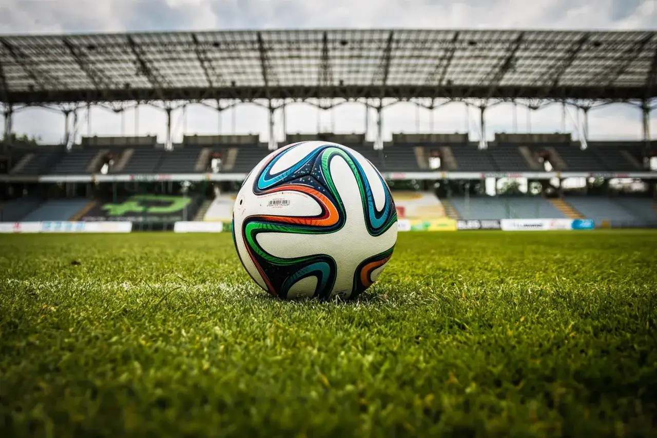Piłka na murawie stadionu, gotowa do gry. Zastanawiasz się, ile trwa dogrywka w piłce nożnej?