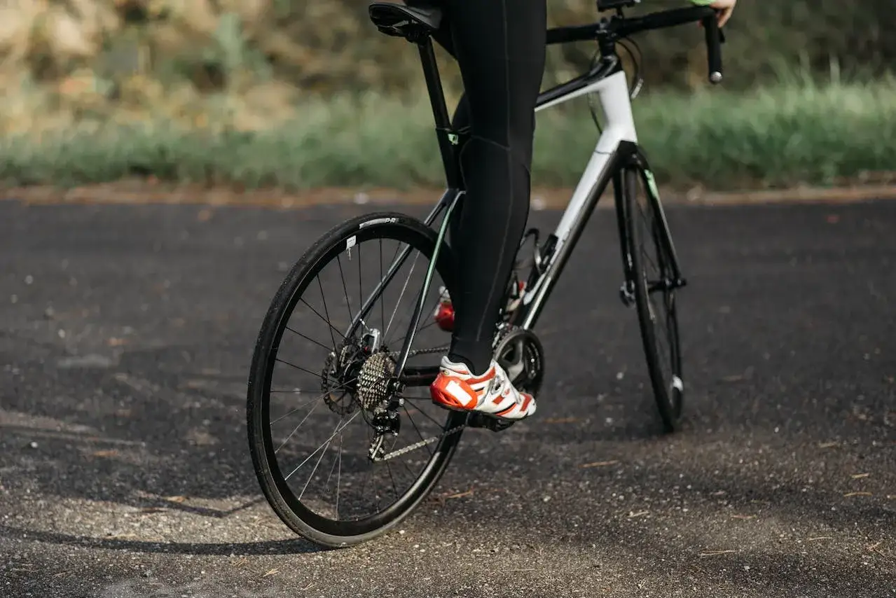 Rowerzysta w czerwono-białych butach pedałuje, dbając o odpowiednią jaką kadencję na rowerze.