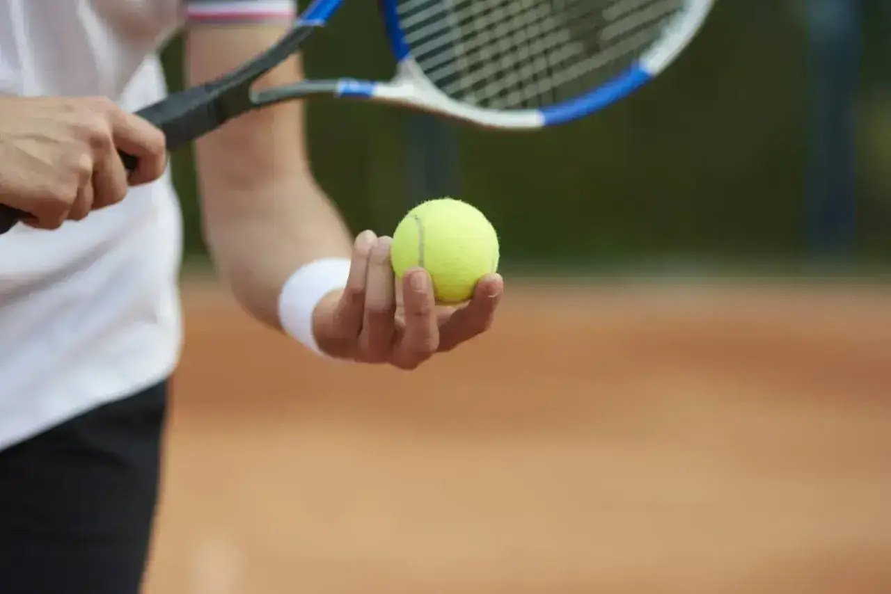 Gracz trzyma piłkę do tenisa, gotowy do serwisu. Kluczowy moment, decydujący o wyniku – tenis tie break.