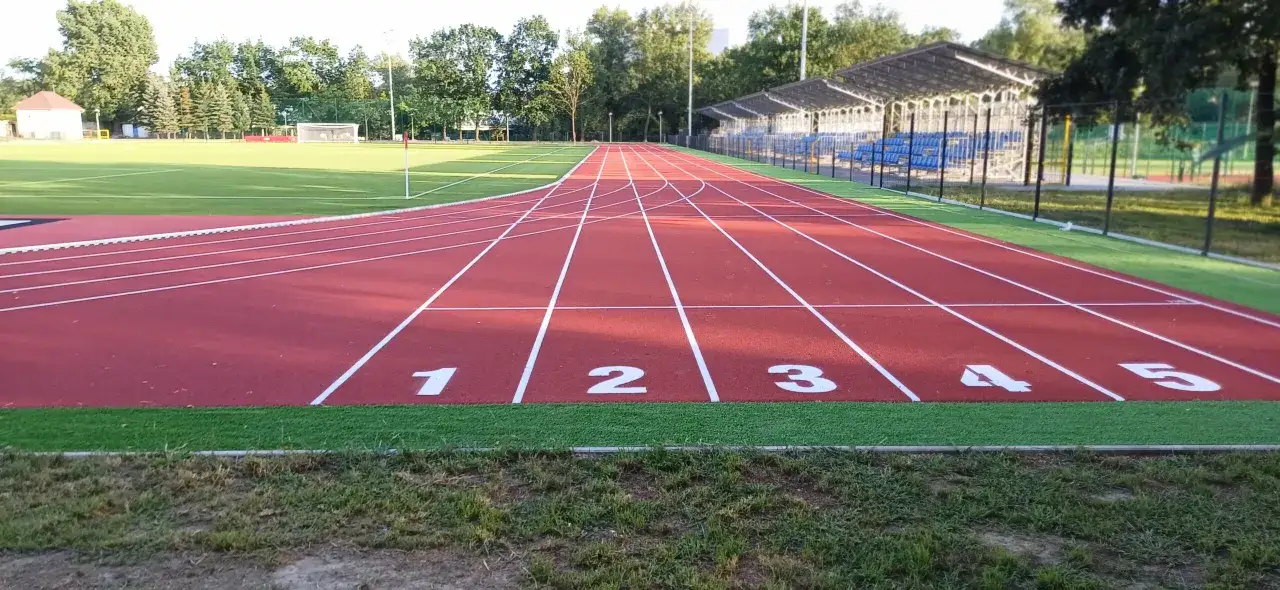 Tor lekkoatletyczny z numerowanymi torami 1-5, gotowy na emocjonujące dyscypliny lekkoatletyczne.