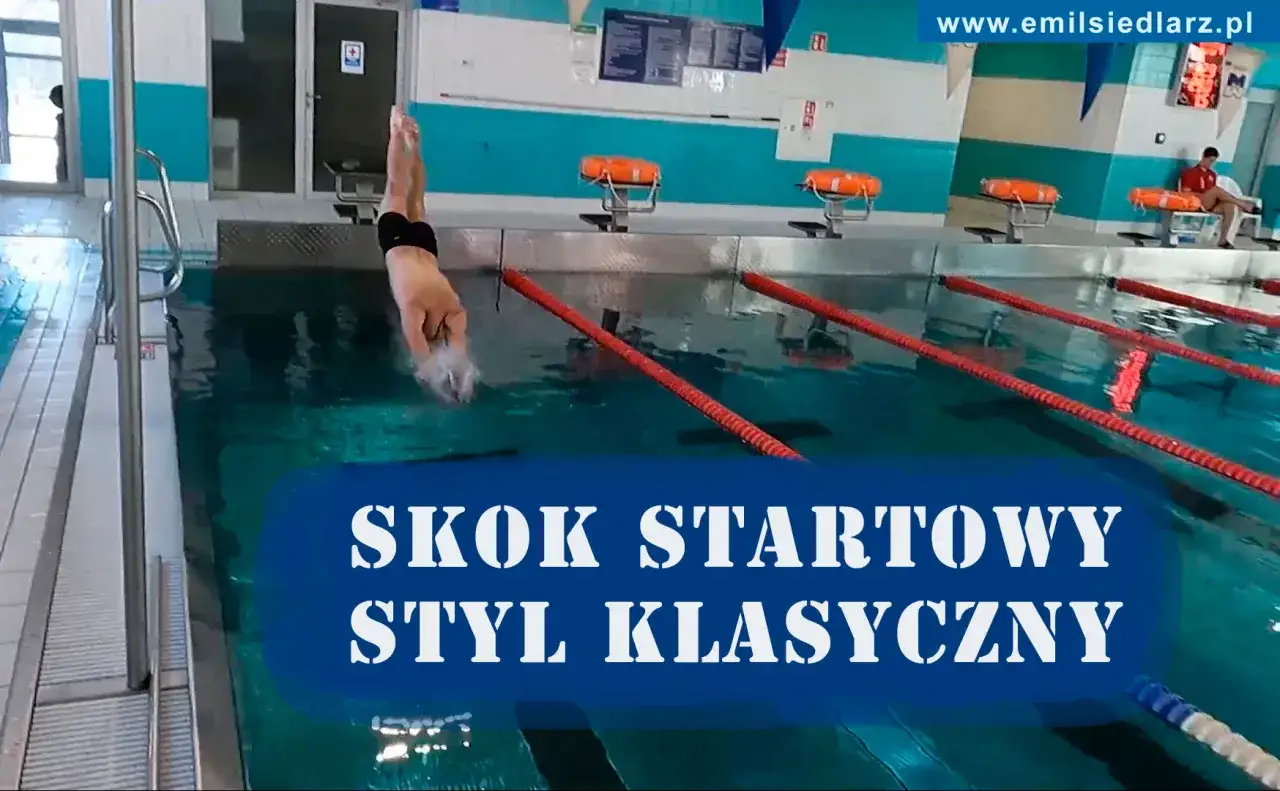Chłopiec skacze do wody w basenie, wykonując skok startowy. To pierwszy krok, by nauczyć się, jak pływać żabką.