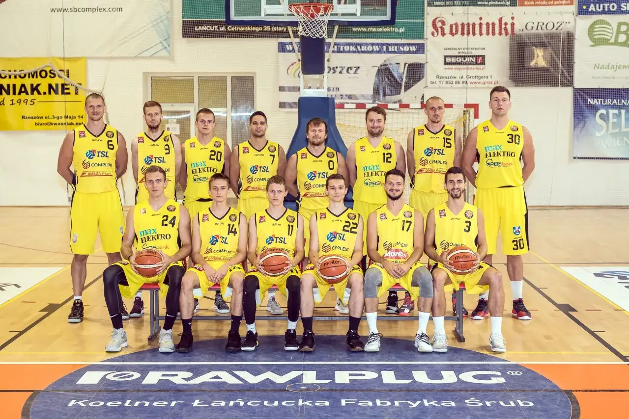 Drużyna koszykarzy w żółtych strojach, pozuje do zdjęcia. W sumie 15 osób gra w kosza.