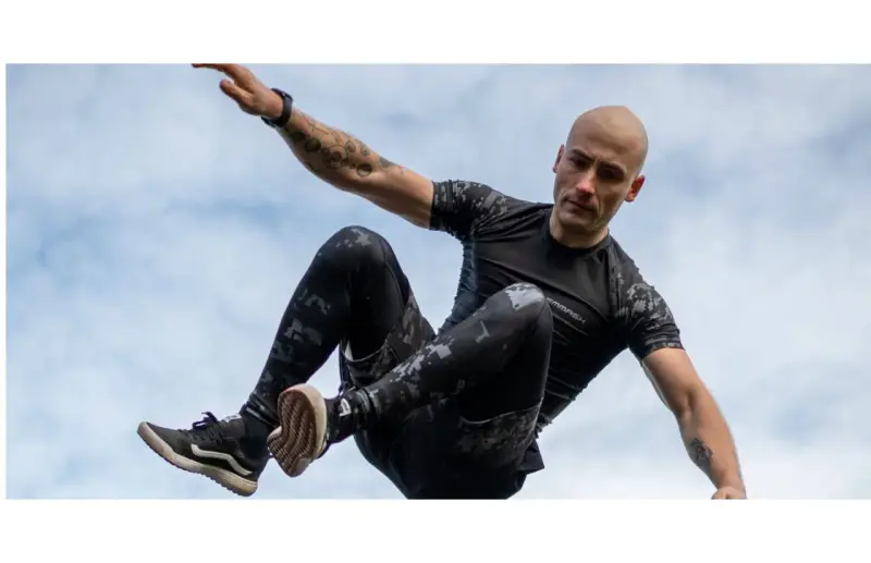 Mężczyzna w ruchu, jakby ćwiczył hiit. Co to za trening? Dynamiczne skoki i akrobacje na tle nieba.